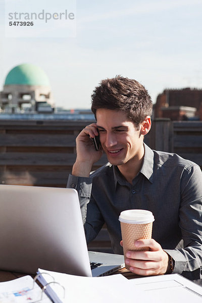 Handy Dach benutzen Mann Notebook Kurznachricht Kaffee multitasking