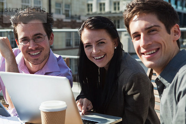 Drei Menschen Lächeln in die Kamera beim benutze ein laptop