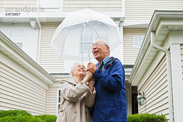 Seniorenpaar mit Regenschirm im Freien