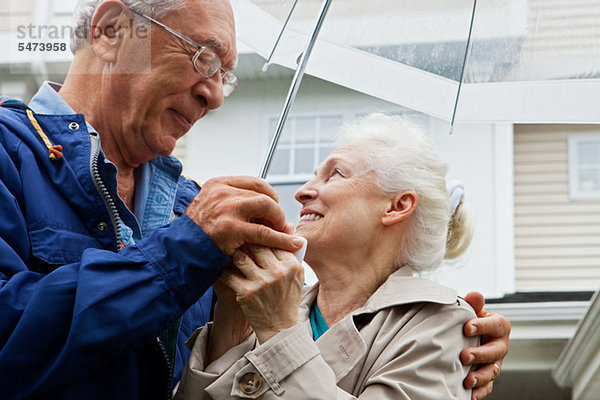 Seniorenpaar mit Regenschirm im Freien