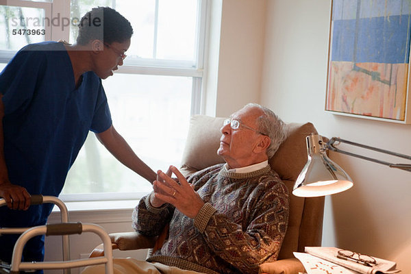 Krankenschwester  die sich um den älteren Mann zu Hause kümmert.