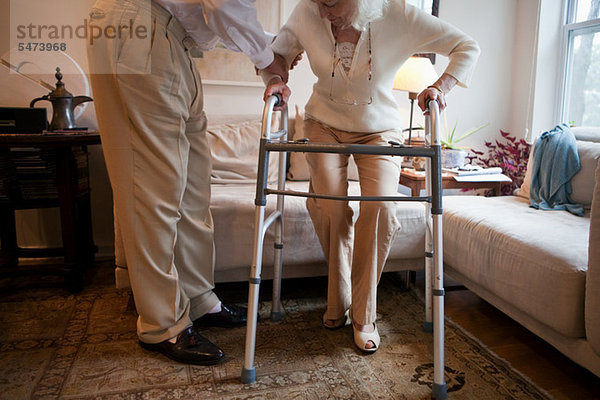 Senior Mann assistierende Ehefrau mit Gehhilfe zu Hause