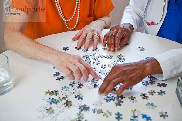 Senior Woman und Arzt mit Jigsaw puzzle