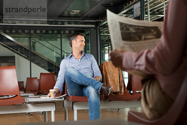 Mitte Erwachsene Mann sitzt in Flughafen Abreise-lounge