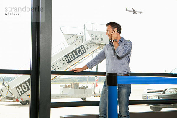 Mitte Erwachsene Mann am Telefon am Flughafen Plattform anzeigen