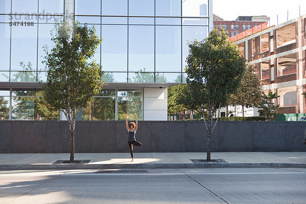 Junge Frau auf der Straße tun Baumes Yoga pose