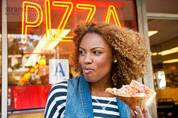 Junge Frau isst Pizzastückchen