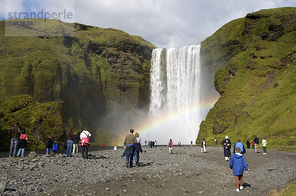 Touristen am Wasserfall SkÛgafoss mit Regenbogen  Südküste  Island  Europa