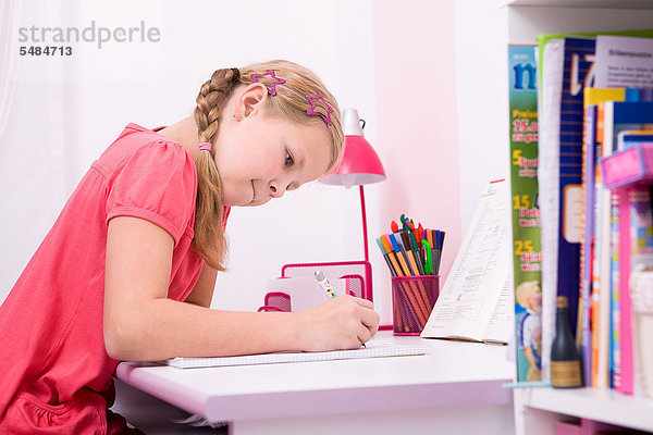 Junge Schülerin bei ihren Hausaufgaben am Schreibtisch