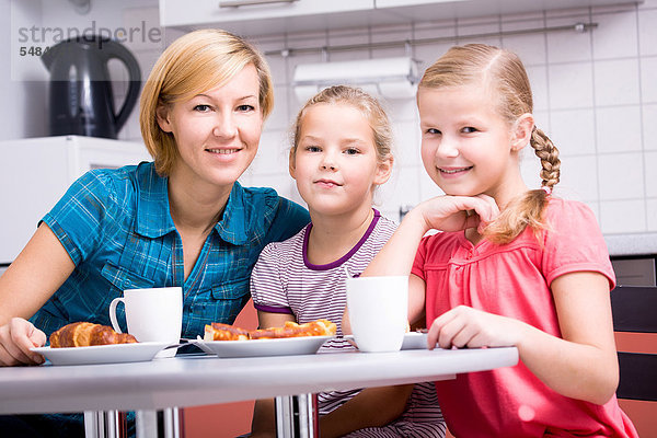 Mutter mit zwei Töchtern beim Frühstück in der Küche