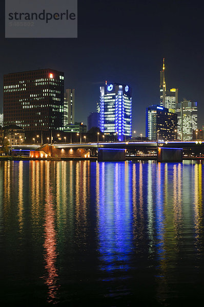 Blick auf die Frankfurter Skyline mit dem beleuchteten Union Investment Building  dem gelb beleuchteten Commerzbank-Turm  dem IG-Metall-Hauptquartier  dem Leben vorne und der Friedensbruecke  vom Südwesten des Main-Flusses in der Nacht  Frankfurt am Main  Hessen  Deutschland  Europa