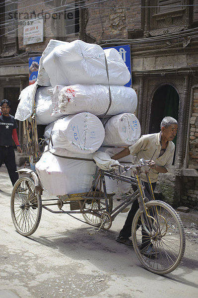 Mann mit einem schwer beladenen Lasten-Fahrrad an einer Straße in Kathmandu  Bagmati  Nepal  Südasien