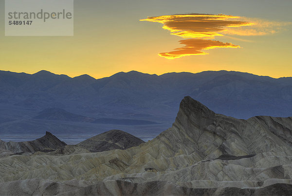 Entstehung einer Sierra Wave Wolkenformation im Abendlicht  Blick von Zabriskie Point  Zabriske Point  auf durch Mineralien verfärbtes erodiertes Gestein des Manly Beacon  dahinter Panamint Range  Sonnenaufgang  Death Valley Nationalpark  Mojave-Wüste  Kalifornien  Vereinigte Staaten von Amerika  USA