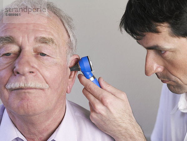 Deutschland  Hamburg  Arzt untersucht Patient mit Otoskop