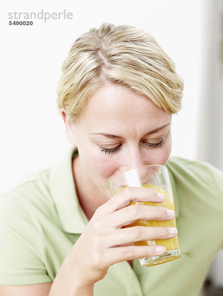 Mittlere erwachsene Frau trinkt Saft