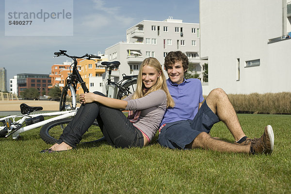 Deutschland  Bayern  Paar im Gras sitzend  lächelnd  Portrait