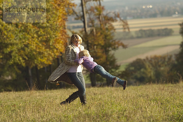 Deutschland  Bayern  Mutter und Tochter spielen im Herbst auf der Wiese