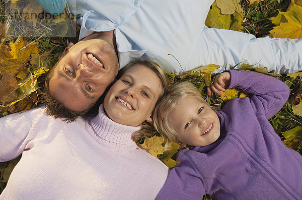 Deutschland  Bayern  Familie im Herbst auf Blättern liegend  lächelnd