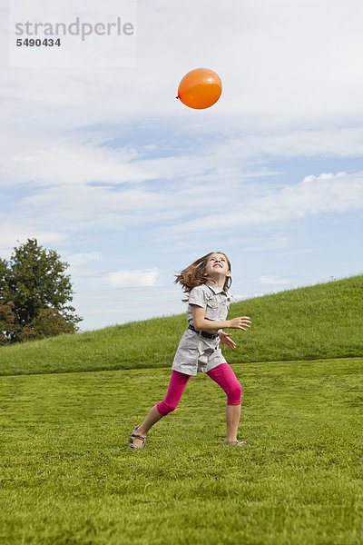Mädchen spielt im Park mit Ballon