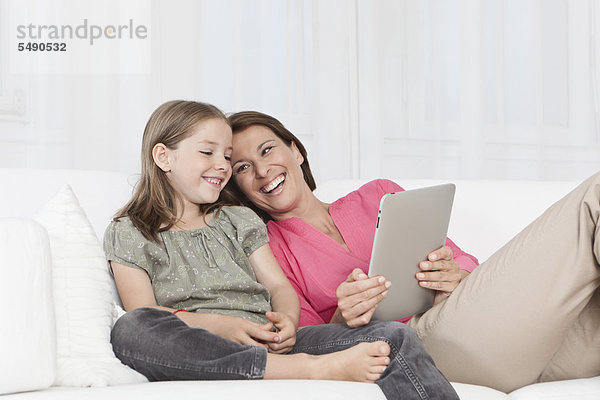 Deutschland  München  Mutter und Tochter mit digitalem Tablett  lächelnd
