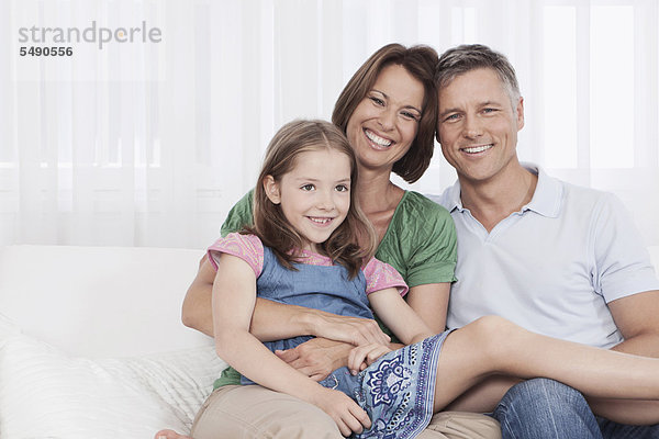 Deutschland  München  Familie auf Couch sitzend  lächelnd