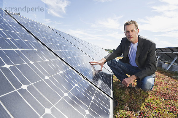 Mann berührt Solarpanel in Solaranlage  lächelnd  Portrait