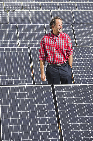Reifer Mann in Solaranlage stehend  lächelnd