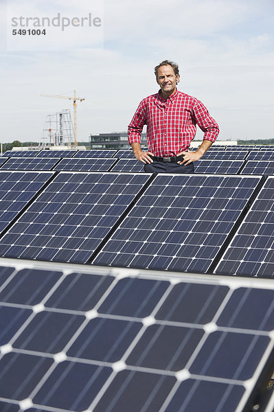 Reifer Mann in Solaranlage stehend  lächelnd  Portrait