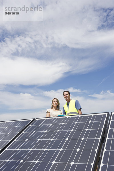 Deutschland  München  Ingenieure stehen in Solaranlage  lächelnd