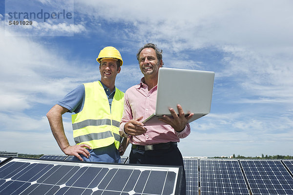 Deutschland  München  Ingenieure mit Laptop in Solaranlage