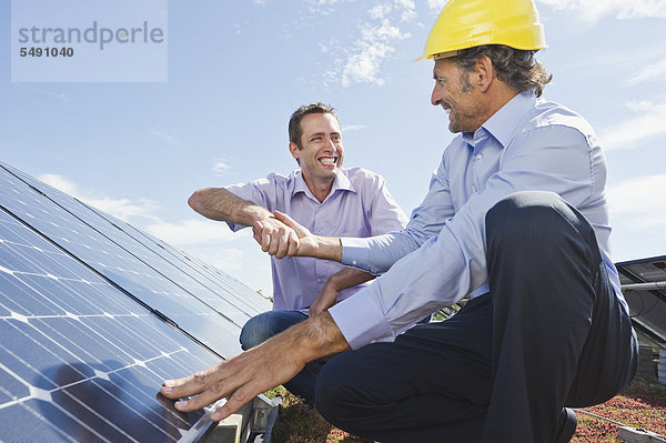 Mann schüttelt sich die Hand mit dem Ingenieur in der Solaranlage  lächelnd