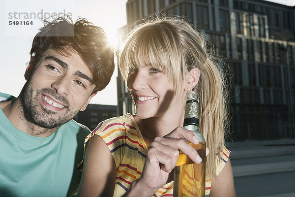 Deutschland  Köln  Junges Paar mit Bierflasche  lächelnd