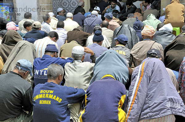 Männer beim Freitagsgebet sitzen vor der überfüllten Moschee auf der Straße  Essaouira  Marokko  Afrika  ÖffentlicherGrund