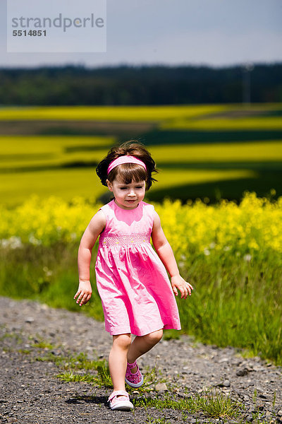 Kleines Mädchen spaziert auf Feldweg