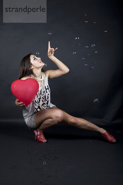 Junge Frau mit Herzballon  weißem Top  High Heels und Seifenblasen