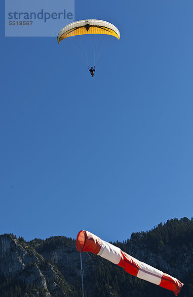 Gleitschirmflieger  Paraglider  beim Landeanflug gegen den Wind vor einem Windsack  hinten Tegelberg  Oberbayern  Bayern  Deutschland  Europa  ÖffentlicherGrund