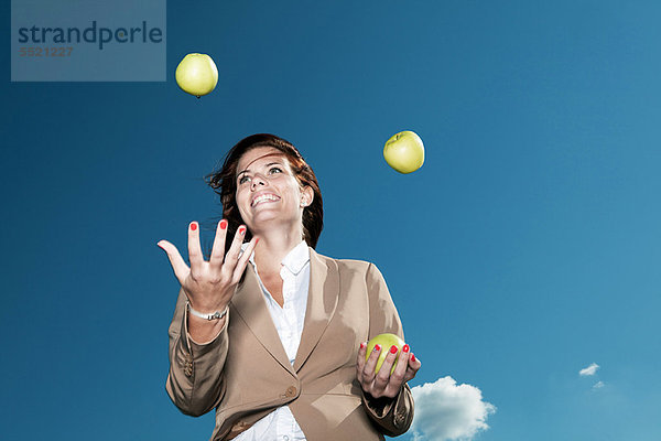 Geschäftsfrau beim Jonglieren mit Äpfeln im Freien