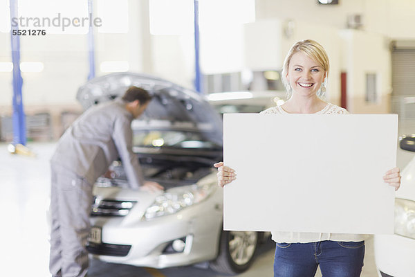 Frau mit leerer Karte in der Garage