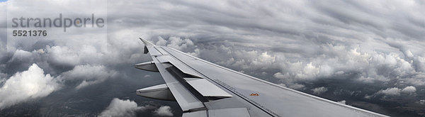 Flugzeugflügel über Wolken fliegend
