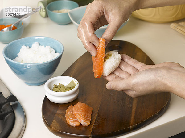 Frau bereitet Sushi bei Tisch zu