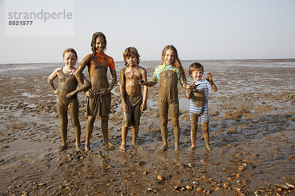Kinder mit Schlamm bedeckt am felsigen Strand