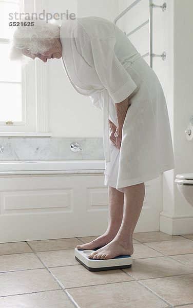 Ältere Frau wiegt sich im Badezimmer