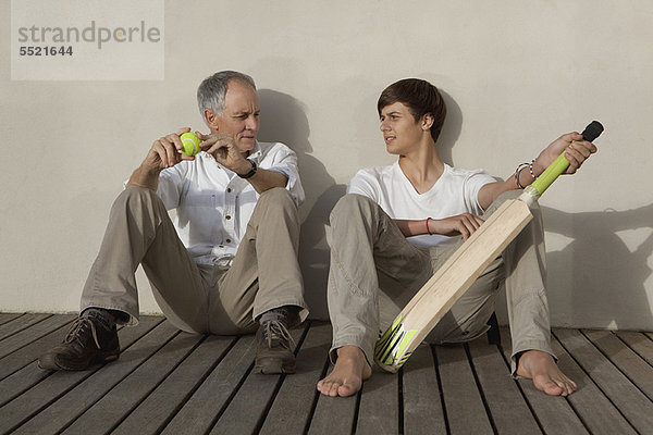 Vater und Sohn mit Kricketschläger auf der Terrasse