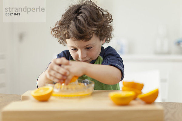 Junge drückt Orangen  um Saft zu machen.