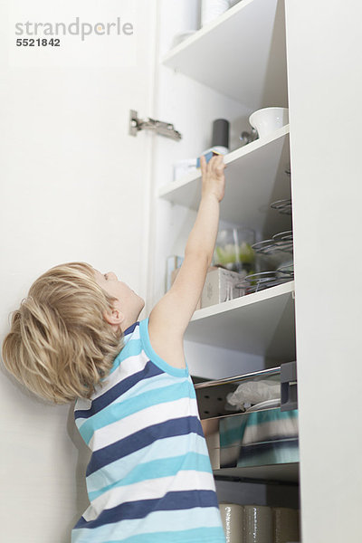 Junge liest für etwas im Schrank