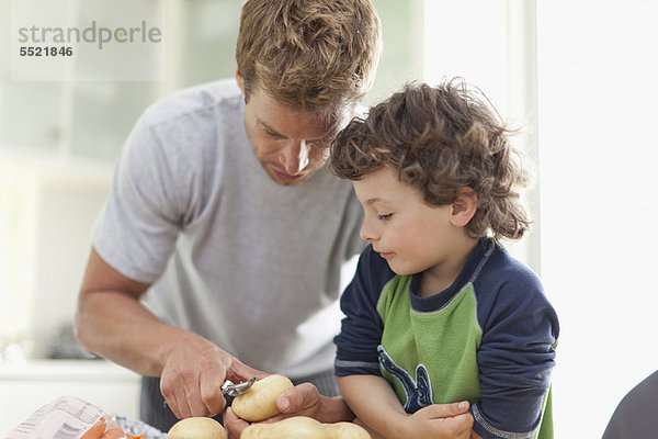 Vater hilft Sohn Kartoffeln schälen