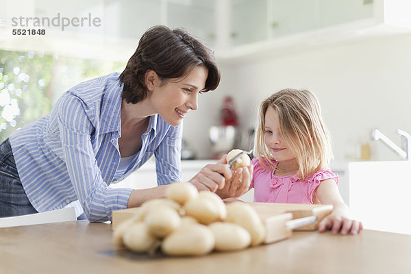 Mutter hilft Tochter beim Schälen von Kartoffeln