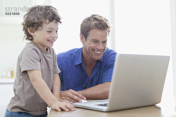 Vater und Sohn nutzen gemeinsam den Laptop