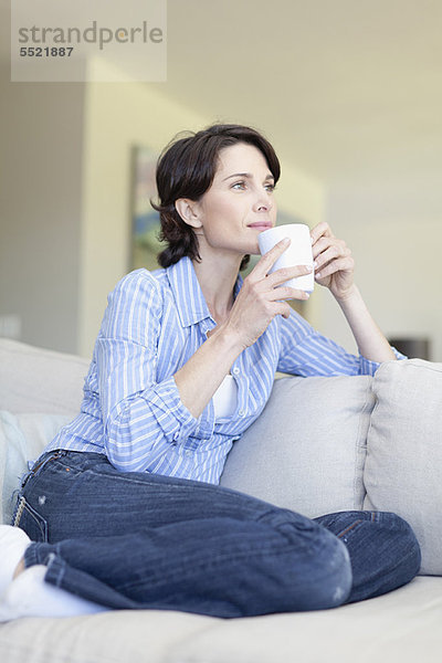 Frau trinkt eine Tasse Kaffee auf der Couch
