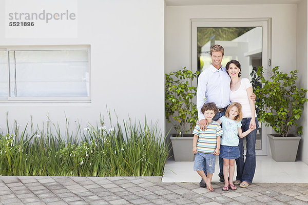 Familie lächelt vor der Haustür